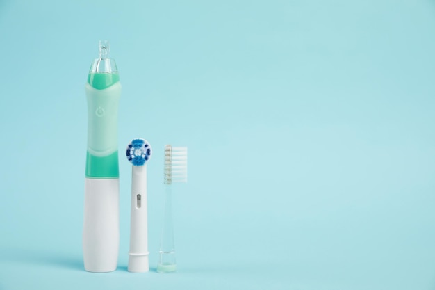 Electric toothbrush and replacement brush heads on light blue background space for text