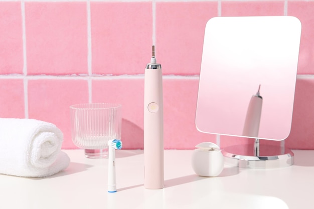 Electric toothbrush towel and mirror on table on pink background