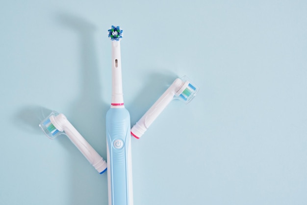 Electric toothbrush with replaceable nozzles on a light blue background copy sapce mock up top view
