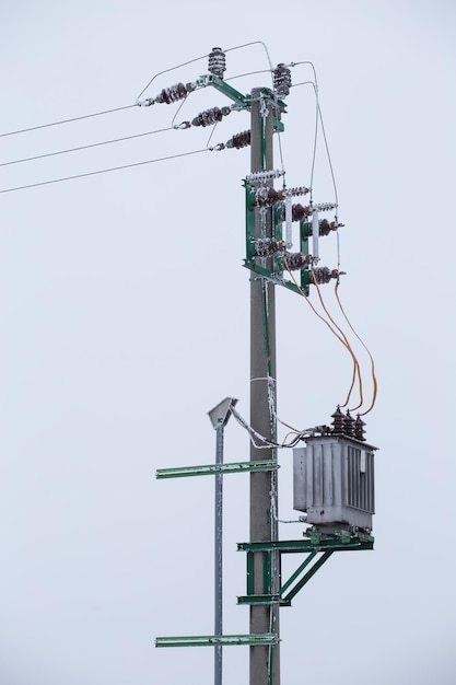 Electric transformer station and wires in winter covered snow and ice