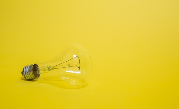 黄色の背景に電気の透明な電球