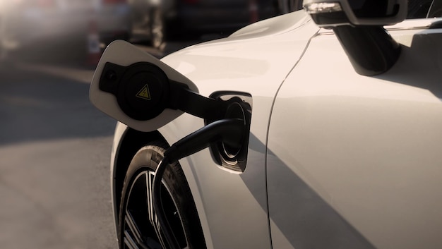 写真 電気自動車 (ev) は電源を充電するステーションに停車し電源ケーブルを接続し電気自動車のバッテリーに電力を充電します 緑のエネルギーとエコパワー 世界の未来の輸送 ev 電力