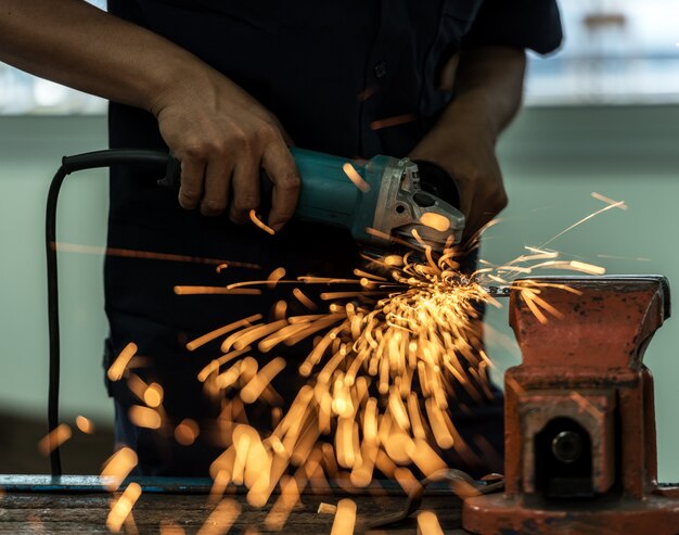 Electric wheel grinding on steel structure in factory