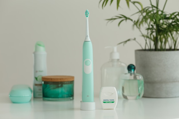 Electric wireless ultrasonic toothbrush with dental floss standing in bathroom