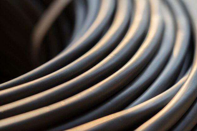 Photo electrical black wire in a roll network connection computer wire cable reel data transmission silhouette of a cable reel in an open air factory warehouse