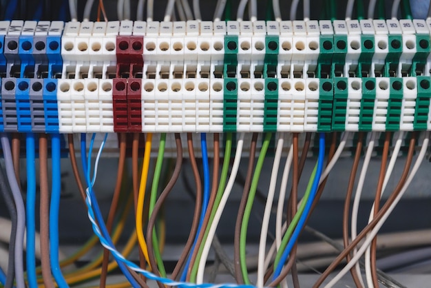 Electrical cabinet with multicolored electric wires connected\
to automatic machines closeup