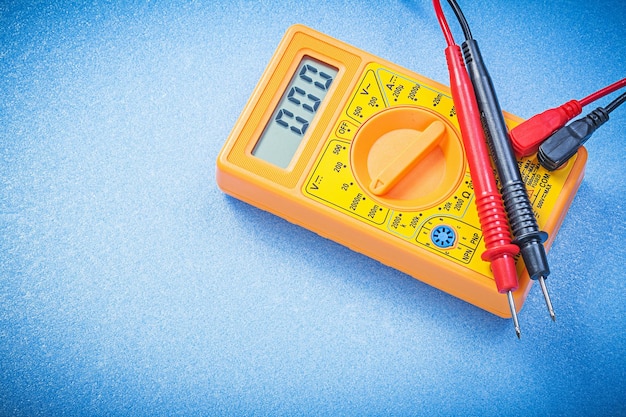 Electrical digital multimeter on blue background directly above electricity concept