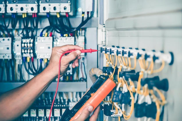 Electrical engineer checking the operation of electrical control cabinet, maintenance concept.