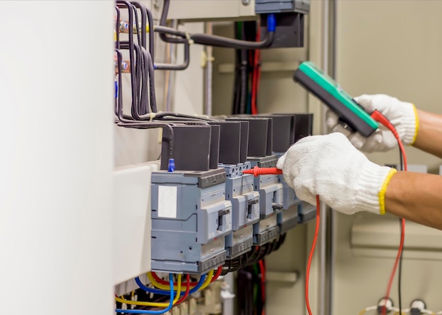 Photo electrical engineer inspecting work of the electrical control cabinet