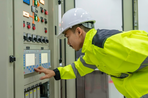 Electrical engineer man checking voltage at the Power Distribution Cabinet in the control roompreventive maintenance YearlyThailand Electrician working at company