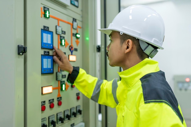 Electrical engineer man checking voltage at the power\
distribution cabinet in the control roompreventive maintenance\
yearlythailand electrician working at company