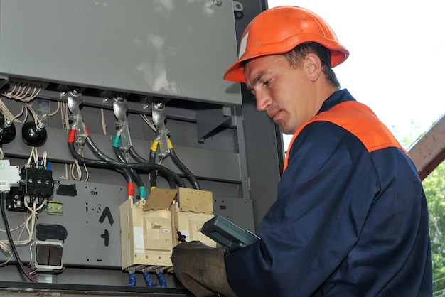 Electrical engineer measures the voltage in an electrical control cabinet.