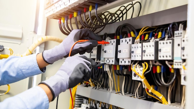 Electrical engineer using digital multi-meter measuring
equipment to checking electric current voltage at circuit breaker
and cable wiring system in main power distribution board.