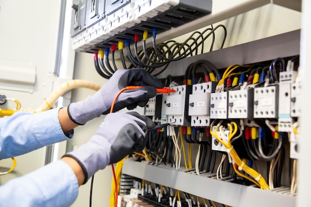 Electrical engineer using digital multimeter measuring\
equipment to checking electric current voltage at circuit breaker\
and cable wiring system in main power distribution board