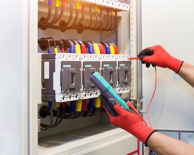 Electrical engineers check electrical control devices with a multimeter