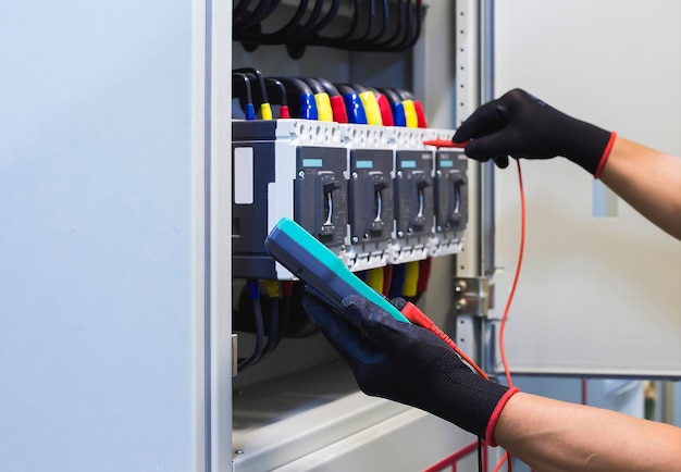 Electrical engineers check electrical control devices with a multimeter