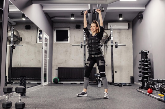 Electrical muscle stimulation Woman in a special black EMS suit performs squats