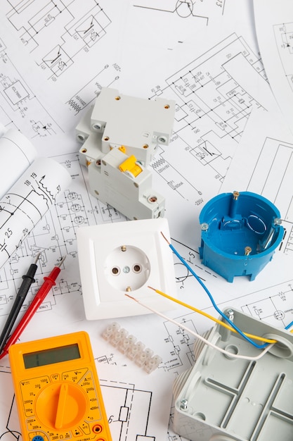 Electrical outlet, switch, circuit breakers, cutting box and digital multimeter. installation of power supply systems with paper drawings