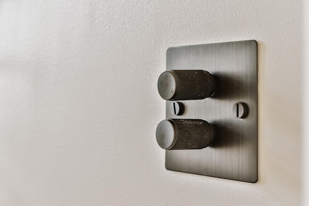 An electrical outlet on the wall in a room with white walls and black metal fittings close up view