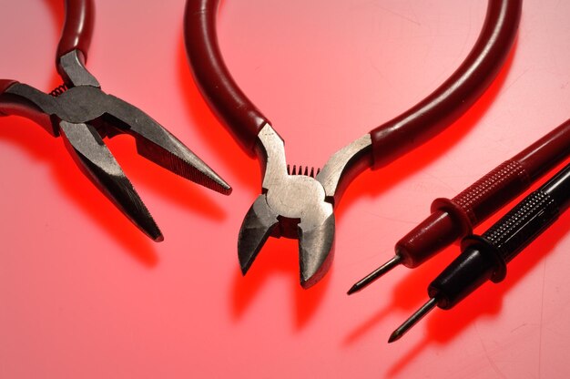 Electrical tools wire cutters multimeter indicator screwdriver Multicolored background Closeup