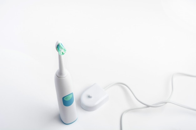 白い背景の上の口腔の衛生のための充電器付き電動歯ブラシ