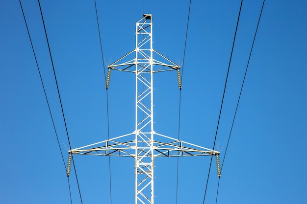 Electrical tower with voltage transmission wires against the background of blue sky High voltage tower power line support with wires for electricity transmission Energy industry