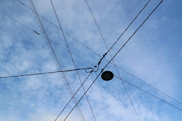 Electrical wires with street lamp against blue sky and white cloud. 