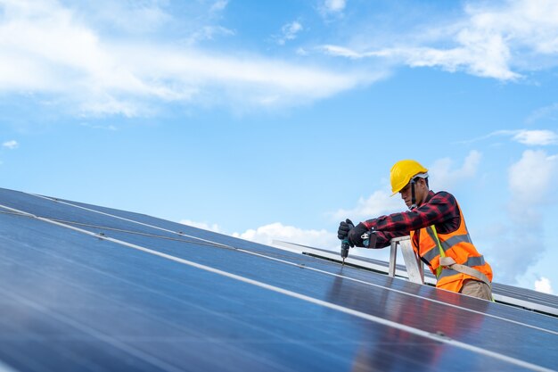 Electrical with instrument technician maintenance electrical\
system,solar panel technician with drill installing solar panels on\
roof at solar panel field.