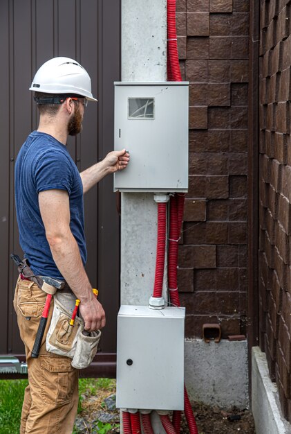 Electrician builder at work, examines the cable connection in the electrical line in the fuselage of an industrial switchboard.