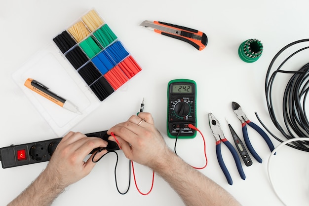 Electrician checking socket voltage with digital multimetetool on white backgroundr. tool on white background