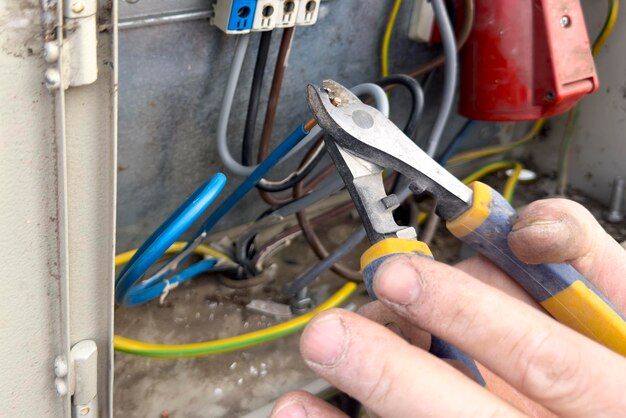 The electrician connects the wires in the shield hands of an electrician closeup with tongs cut off
