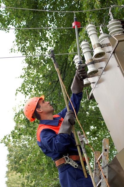 The electrician controls the voltage on the power transmission line before repairing the substation