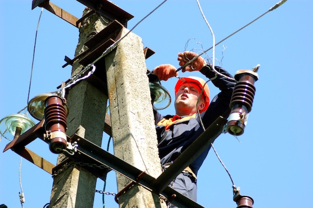 Electrician on an electric pole changes a damaged insulator