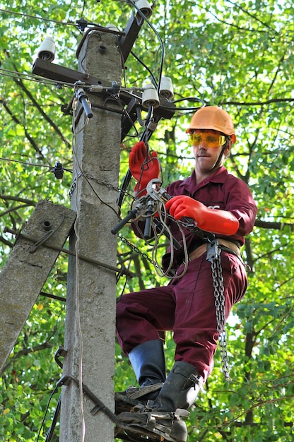 An electrician on an electric pole repairs wires on a power\
line