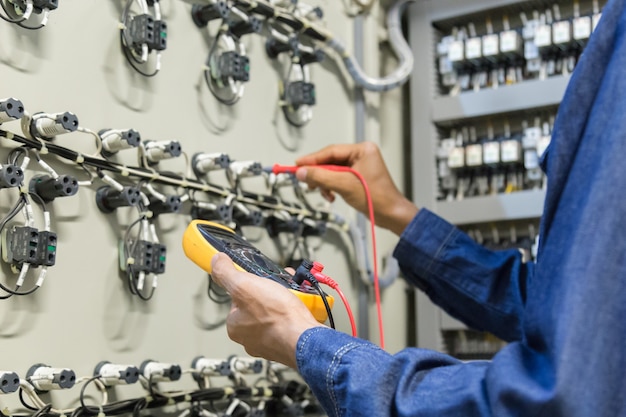 Electrician engineer work  tester measuring  voltage and current of power electric line in electical cabinet control.