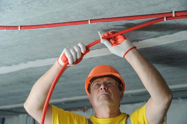 Electrician fixing an electric corrugated tube to the ceiling