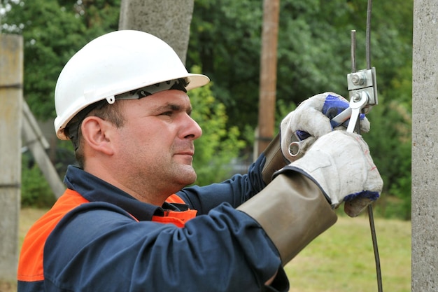 An electrician grounds an electric pole