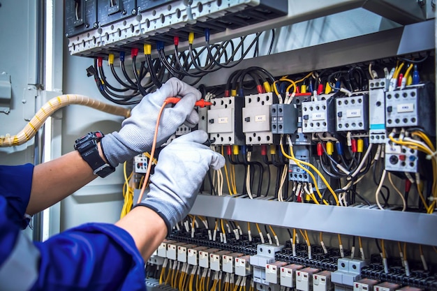 Electrician hand and voltmeter checking electric current voltage at circuit breaker