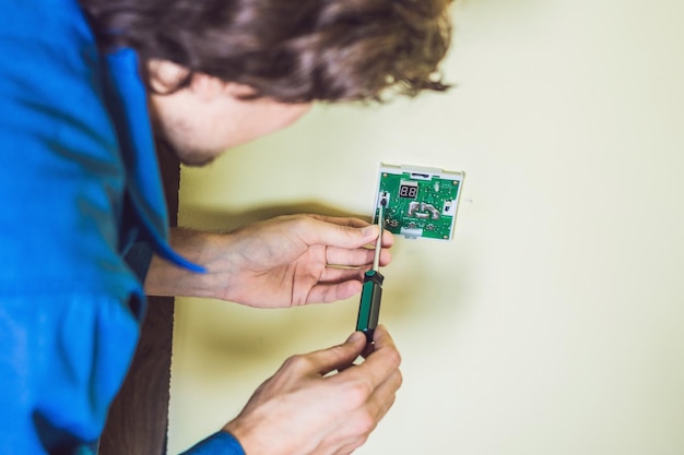 Electrician installing an electrical thermostat in a new house.