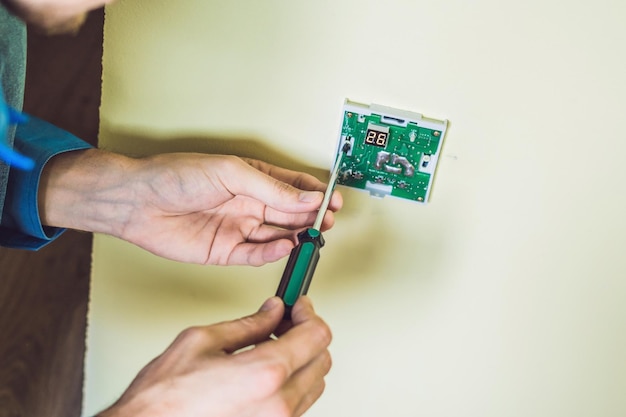 Electrician installing an electrical thermostat in a new house.