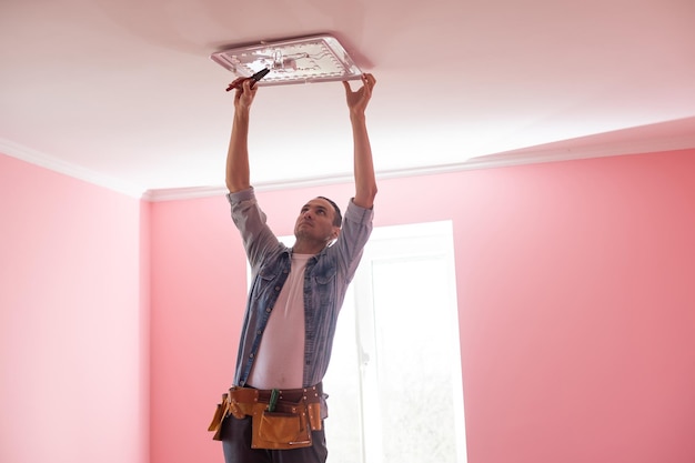 Electrician installing a led light on the ceiling.