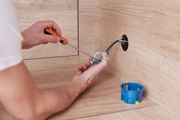 Electrician installing a socket plug in the kitchen.