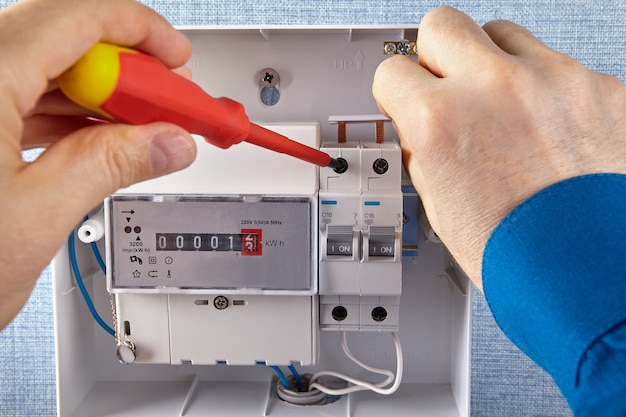 An electrician installs of electrical panel with circuit breakers and an electricity meters.