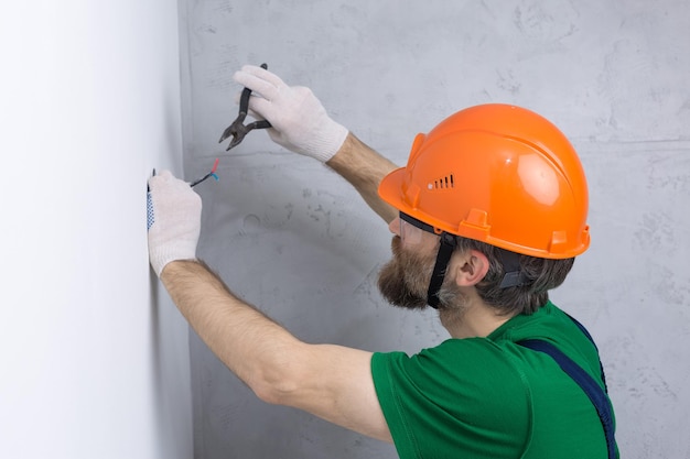 An electrician installs sockets in the apartment A guy in an orange helmet makes electrics