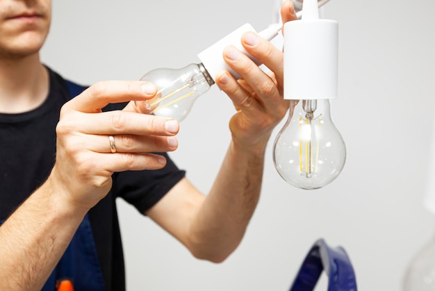 The electrician is installing the led light bulbs into the chandelier