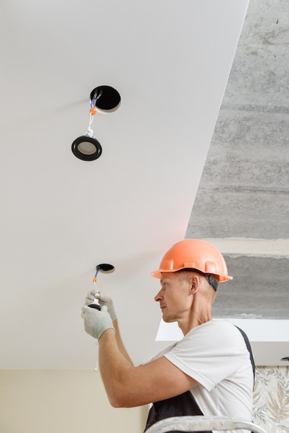 L'elettricista sta installando faretti a led sul soffitto.