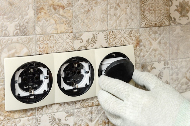 An electrician is installing switches and sockets on the wall close up