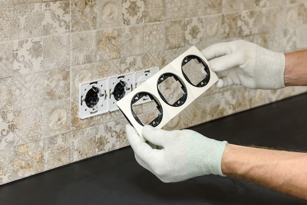 An electrician is installing switches and sockets on the wall.