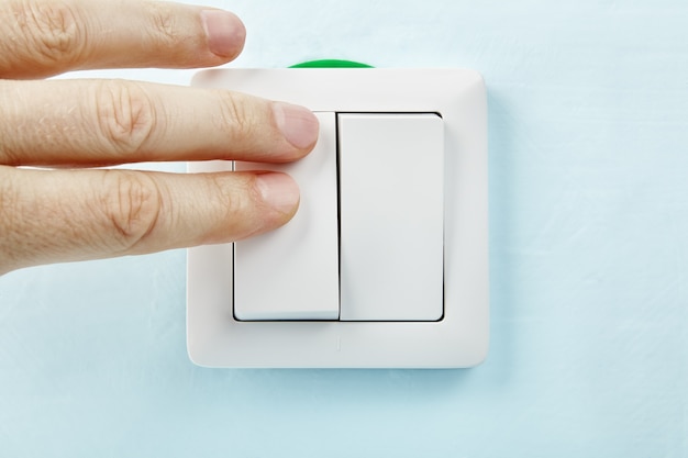 Electrician is pressing button of new European standard  light switch, electrical installation.