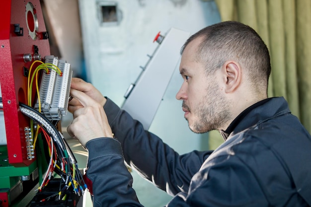 Electrician on overalls is working with energy panel and machinery equipment on plant